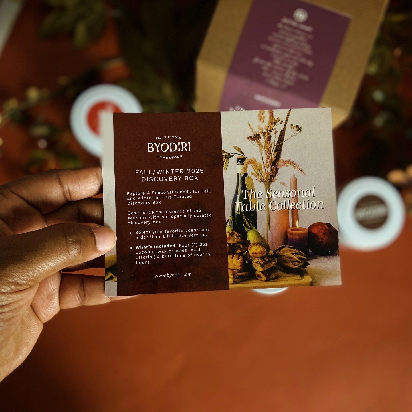 Hand holding a Byodiri Fall/Winter 2025 Discovery Box flyer with a blurred background