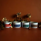 Four 2-oz fall candle containers with labels on a brown surface with decorative elements.