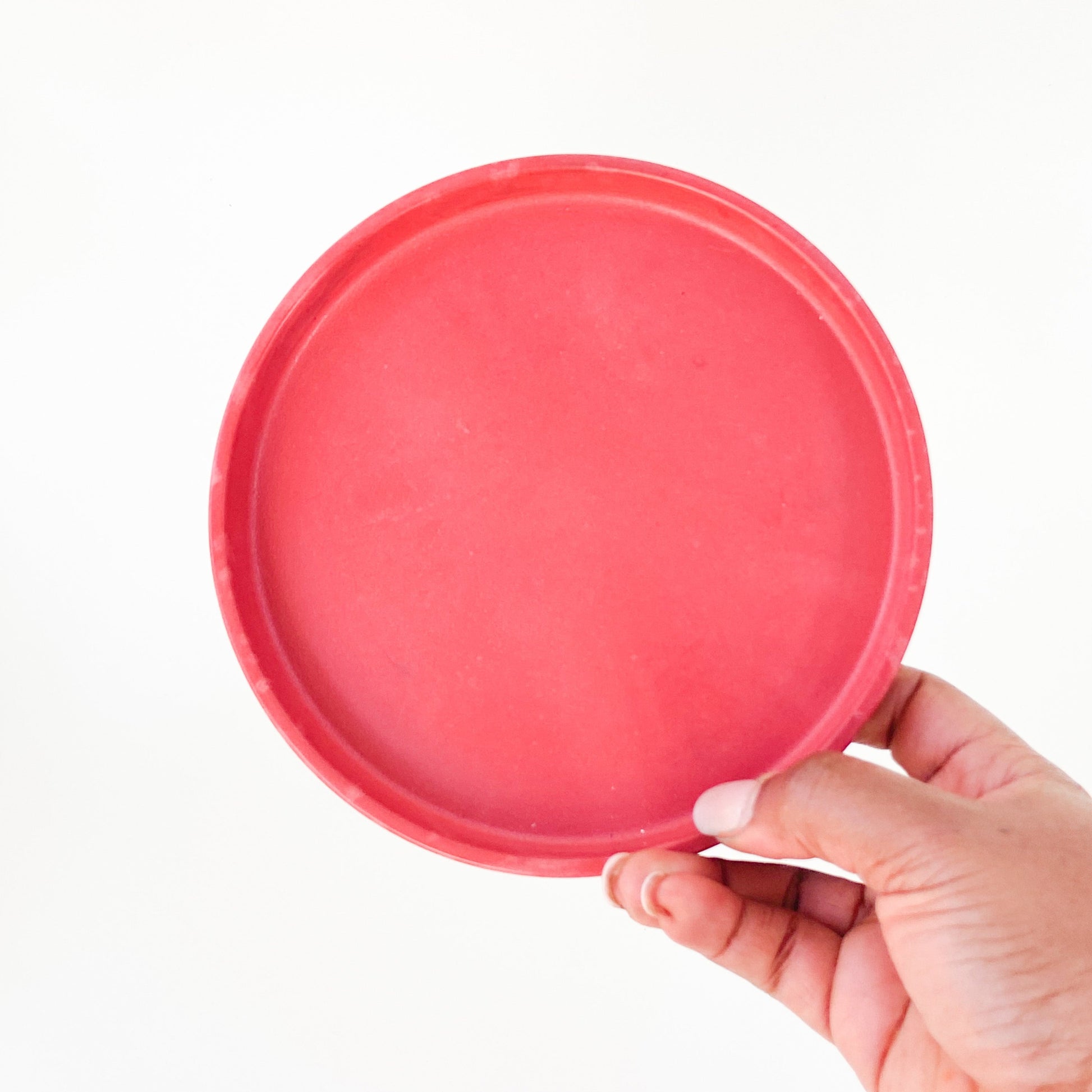 Hand holding a red round catch all tray